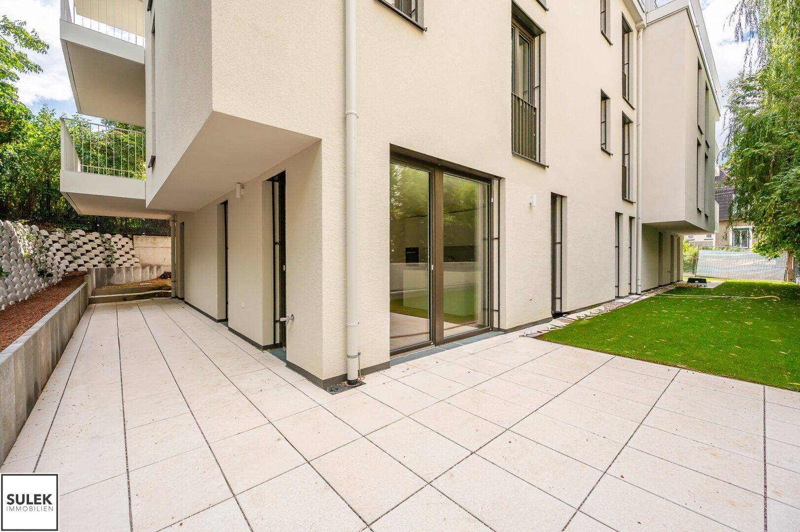 Großzügige, geflieste Terrasse am modernen Gebäude, ideal für entspannte Stunden im Freien.
