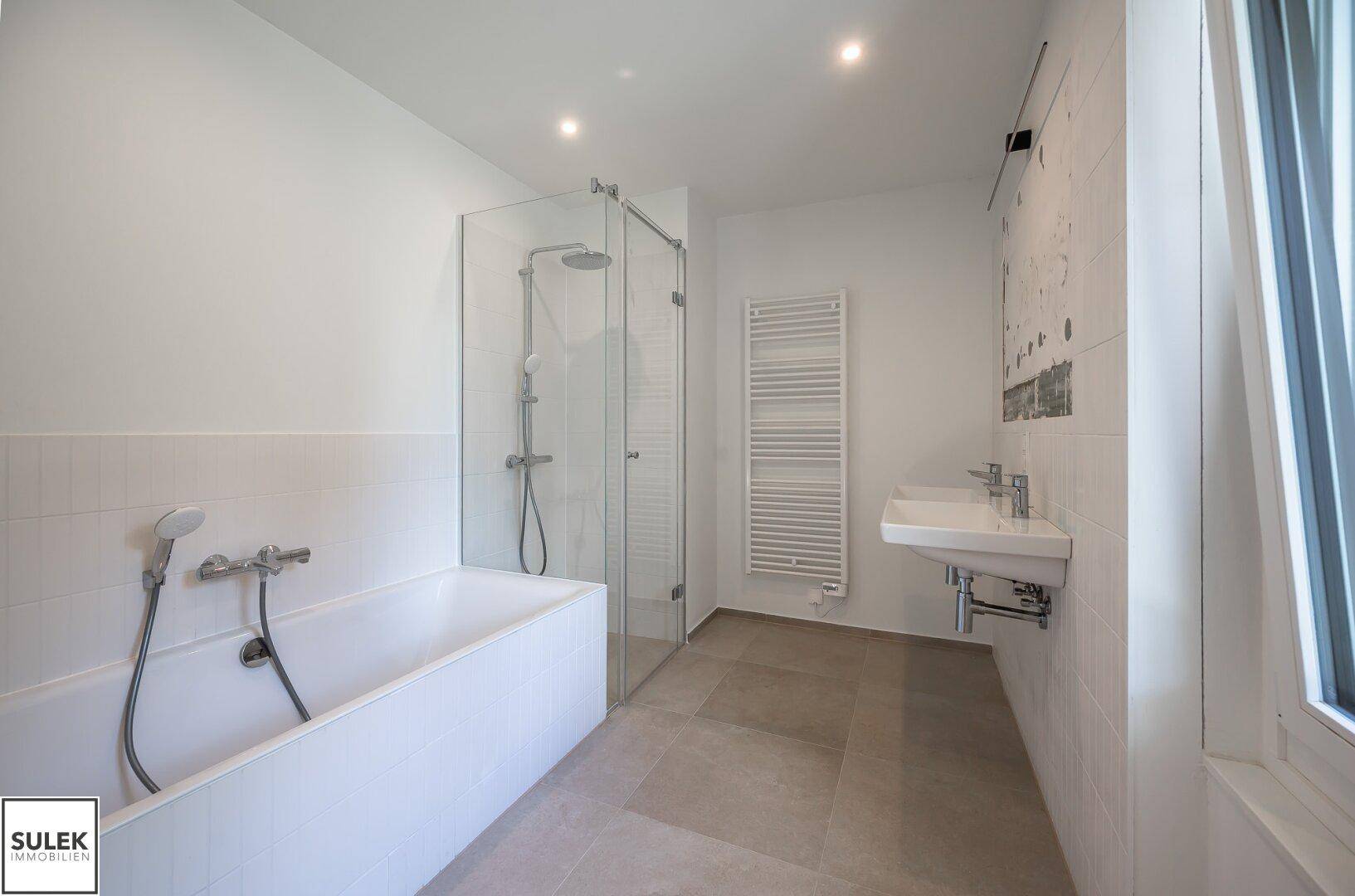 Modernes Badezimmer mit Badewanne, Glasdusche und einem eleganten Waschbecken.