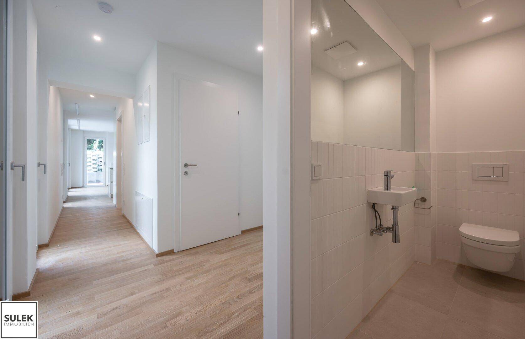 Heller Flur mit Holzboden und direktem Zugang zu einem modernen Gäste-WC.