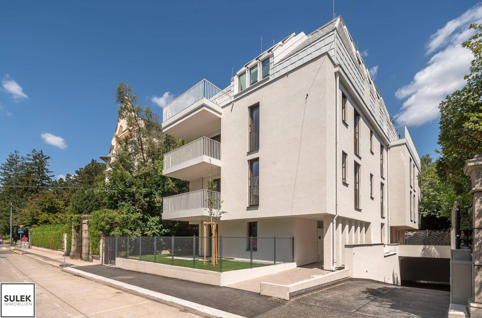 Moderne Fassade des Neubaus mit Balkonen und der Zufahrt zur Tiefgarage.