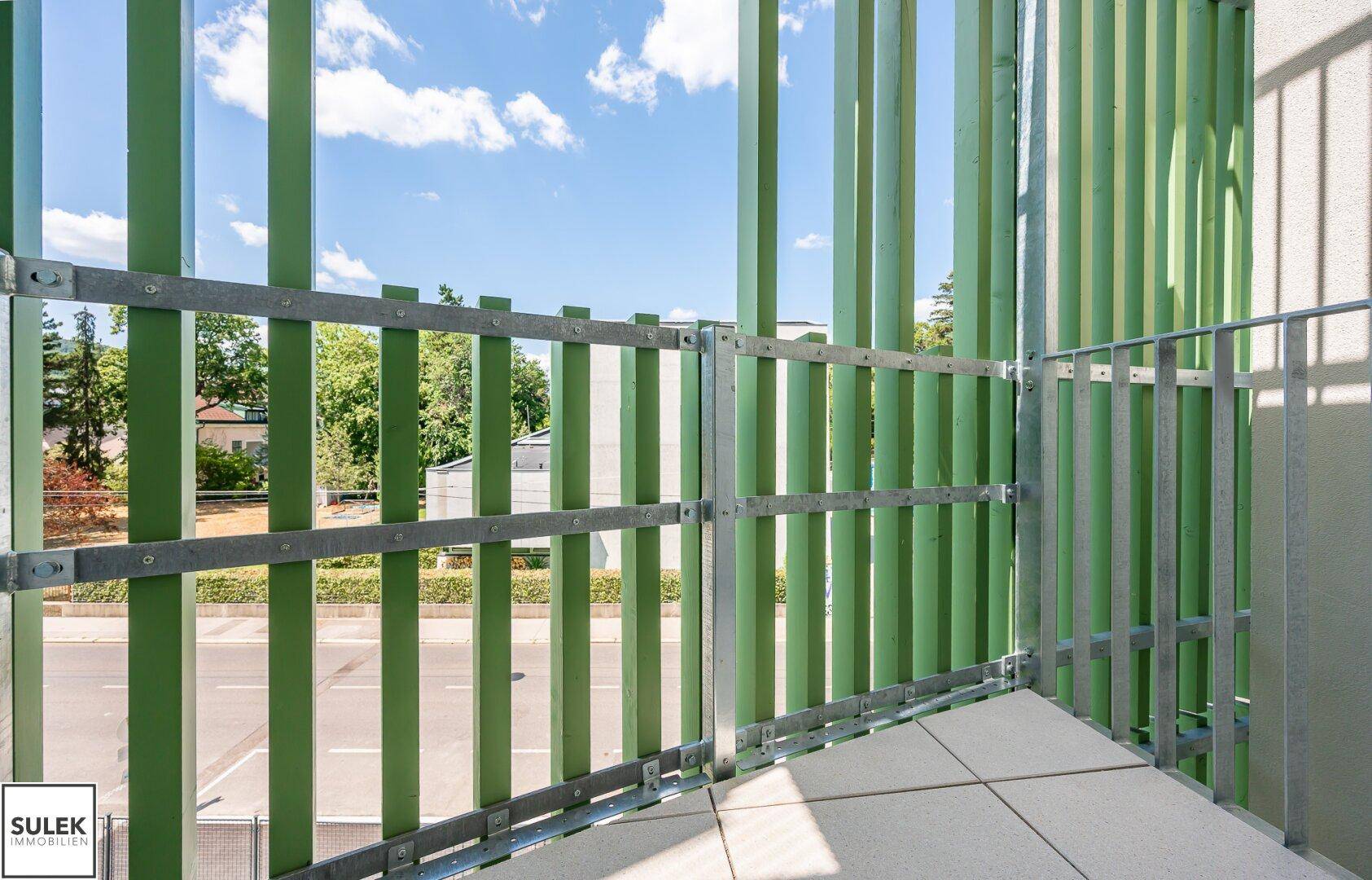 Detailansicht des Balkons mit grünen vertikalen Lamellen, die Sichtschutz und modernes Design bieten.