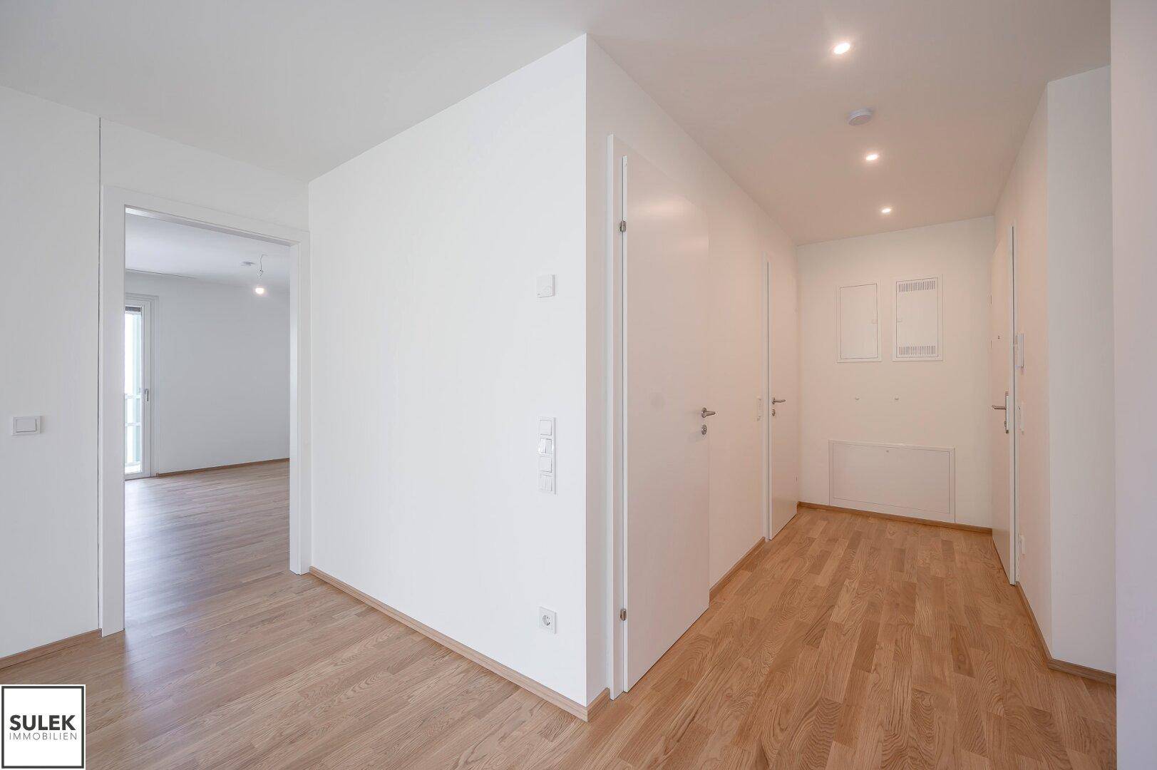 Heller Flur mit Parkettboden und Einbaustrahlern, führt zu den verschiedenen Wohnbereichen der Wohnung.