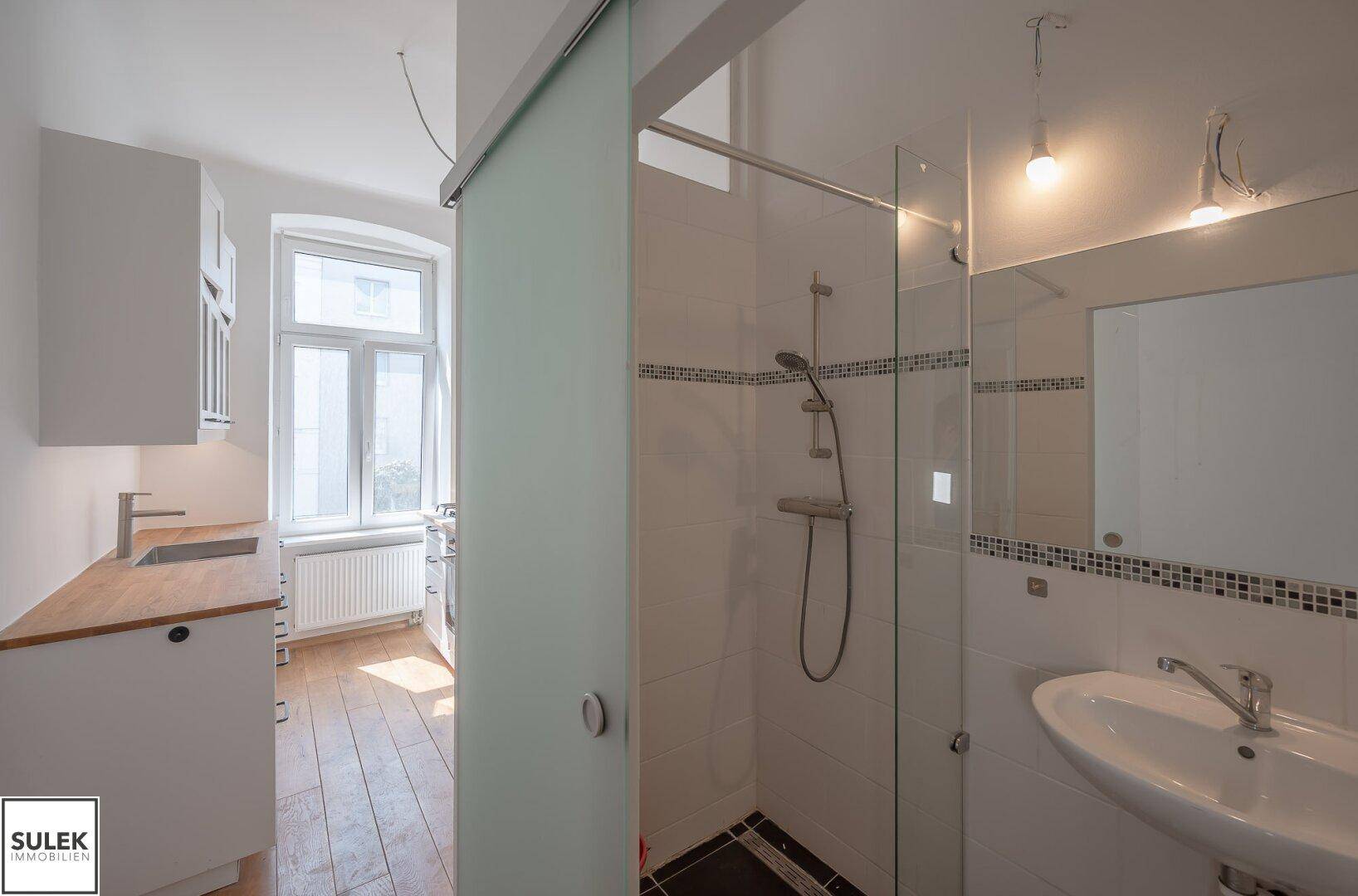 Modernes Badezimmer mit Duschkabine, Waschbecken und weißen Fliesen.