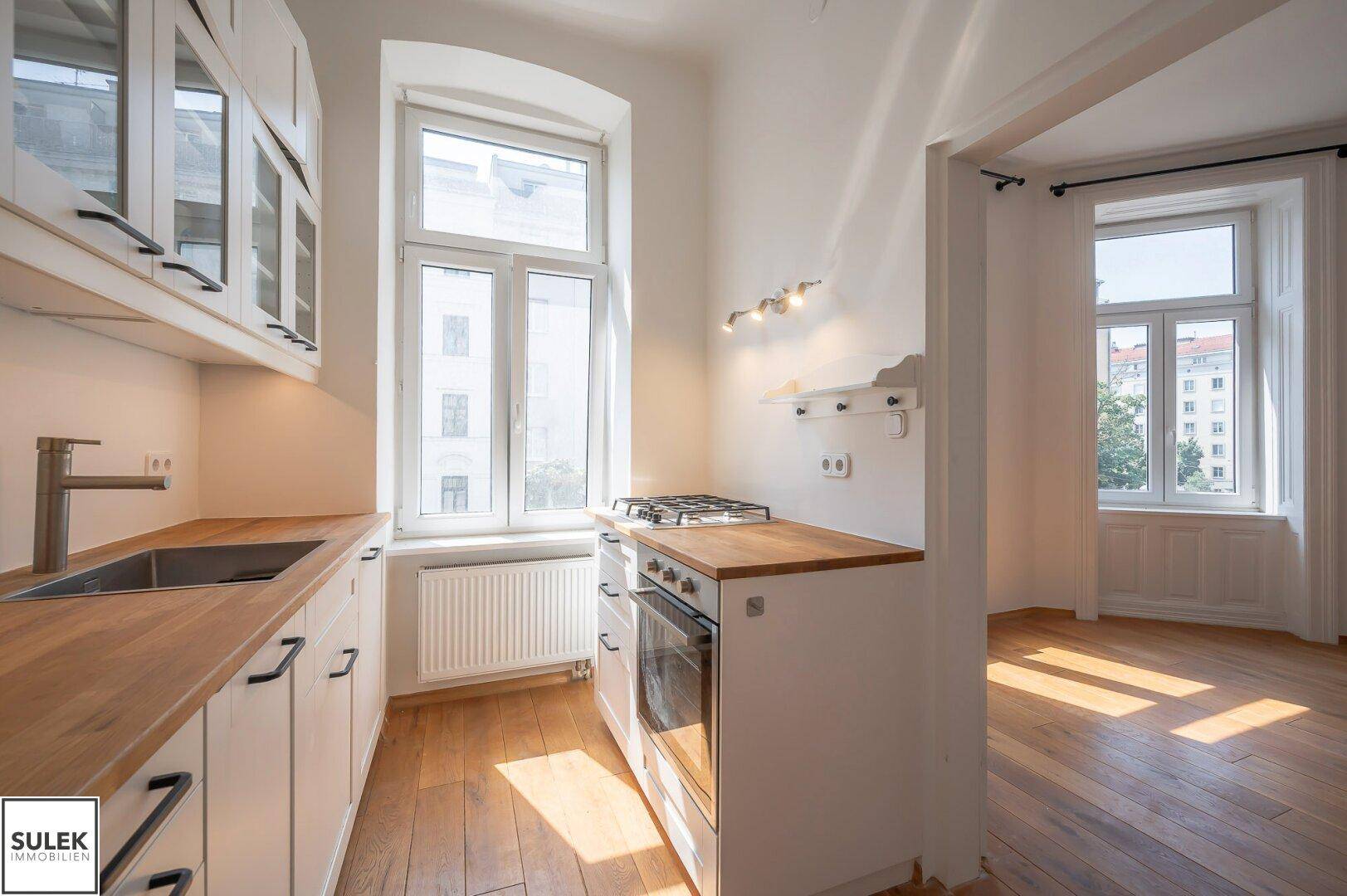 Funktionale Küche mit Holz-Arbeitsplatten, Gasherd und Blick in den angrenzenden Raum.