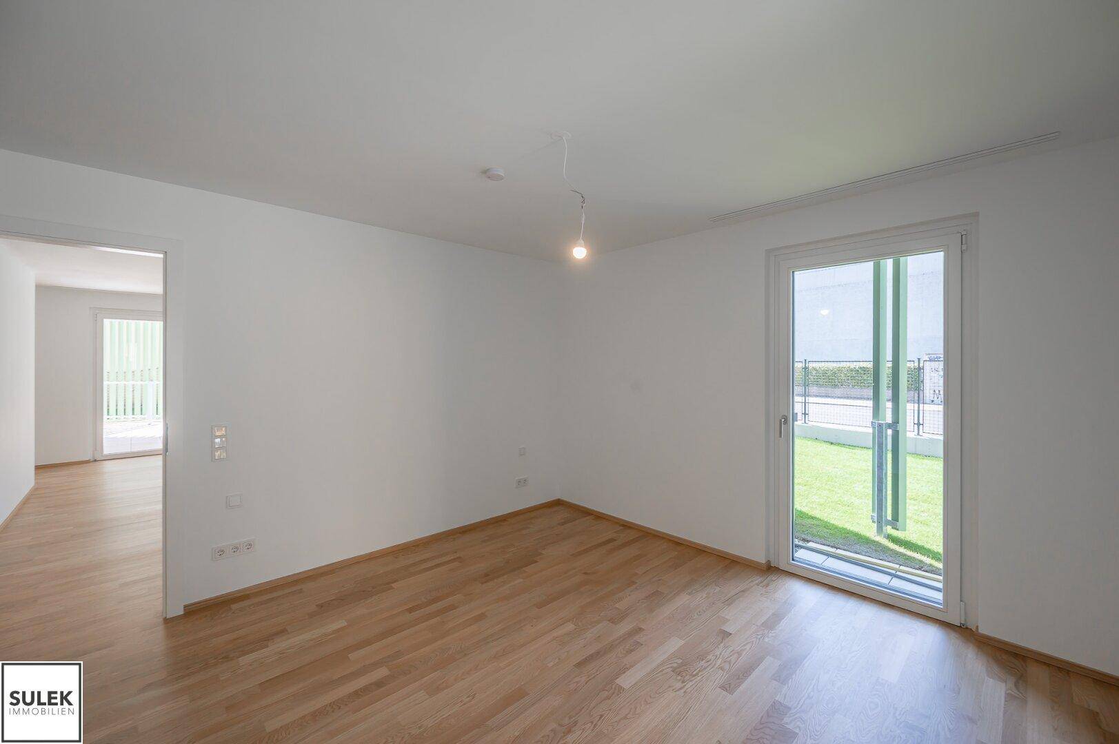 Geräumiges Schlafzimmer mit Holzboden und Zugang zu einem kleinen Außenbereich.