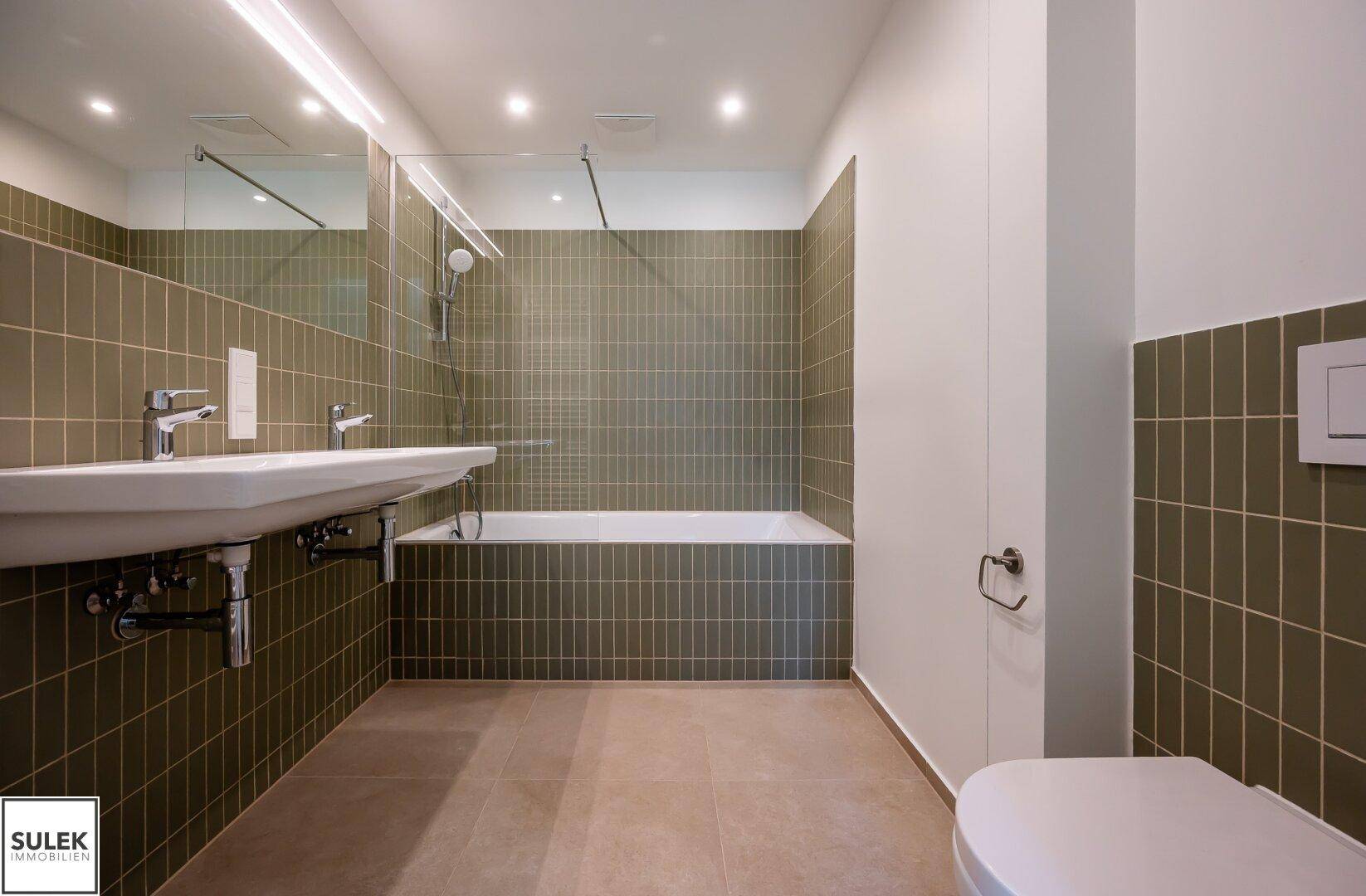 Helles Badezimmer mit Badewanne, Waschtisch und wandhängendem WC in modernem Design.