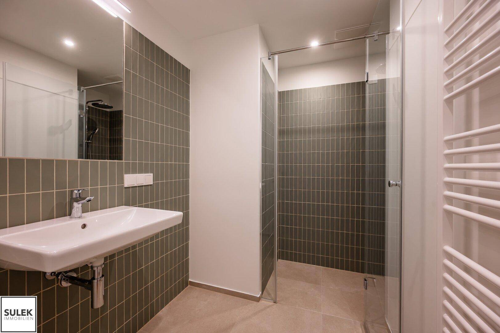 Modernes Badezimmer mit ebenerdiger Dusche, Waschtisch und beheiztem Handtuchhalter.