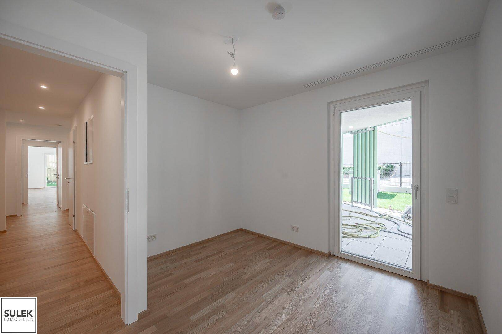 Helles Zimmer mit Parkettboden und direktem Zugang zu einem Außenbereich.