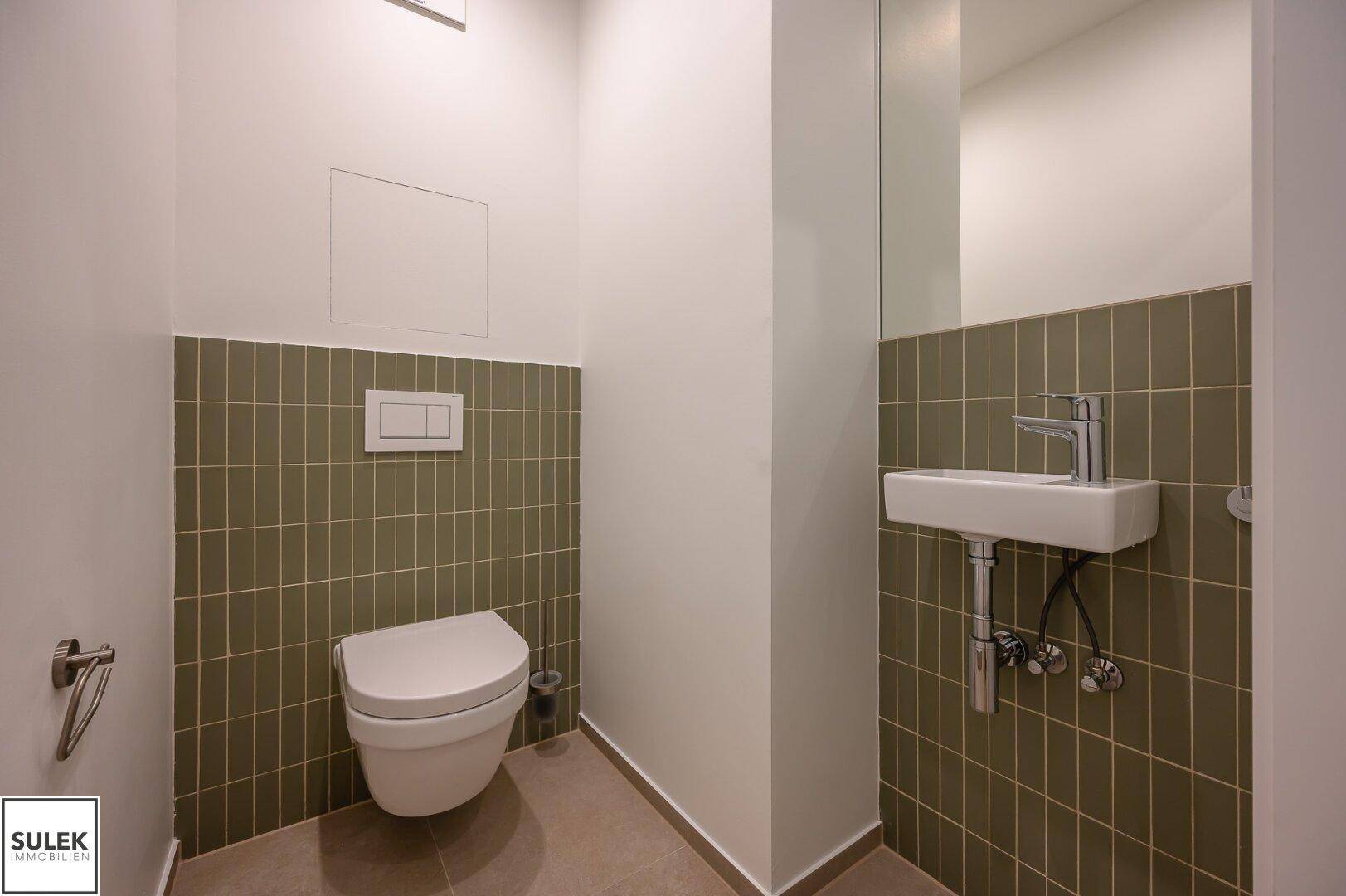 Modernes Gäste-WC mit wandhängender Toilette und kleinem Waschtisch.