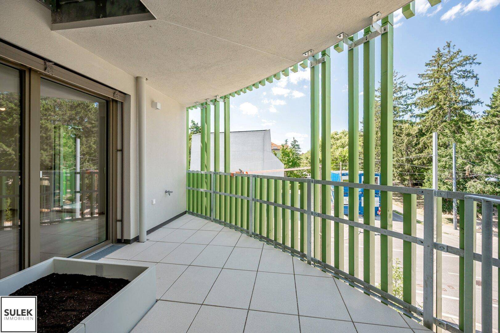 Geräumiger Balkon mit Fliesenboden und modernen grünen Sichtschutzelementen, bietet viel Privatsphäre.