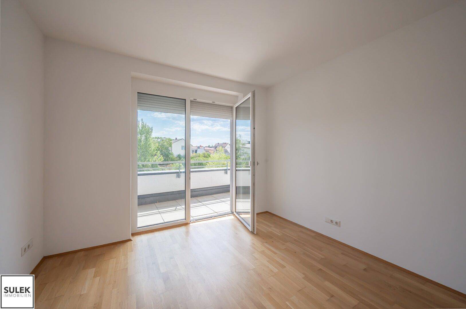 Geräumiges, helles Wohnzimmer mit Parkettboden und direktem Zugang zum Balkon.