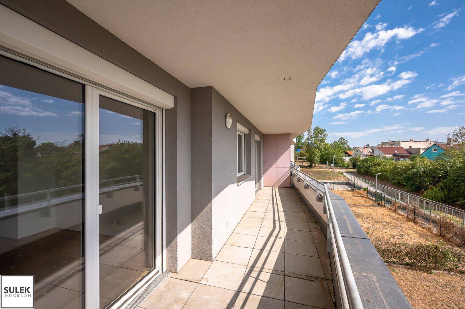 Geräumiger Balkon mit Fliesenboden und Blick auf die umliegende Wohnbebauung.