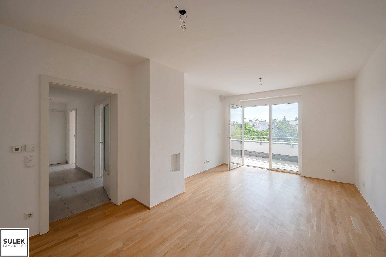 Geräumiges Wohnzimmer mit Parkettboden und direktem Zugang zu einem großen Balkon.