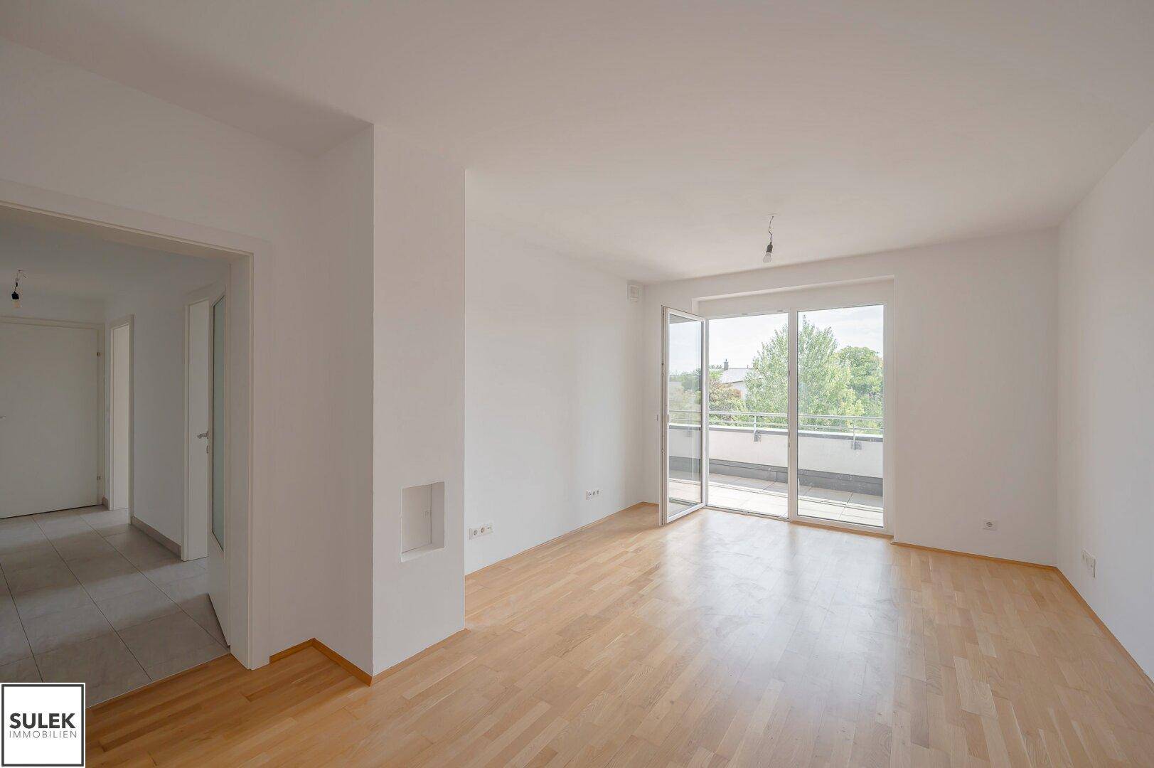 Großes, lichtdurchflutetes Wohnzimmer mit Parkettboden und Zugang zu einem sonnigen Balkon.