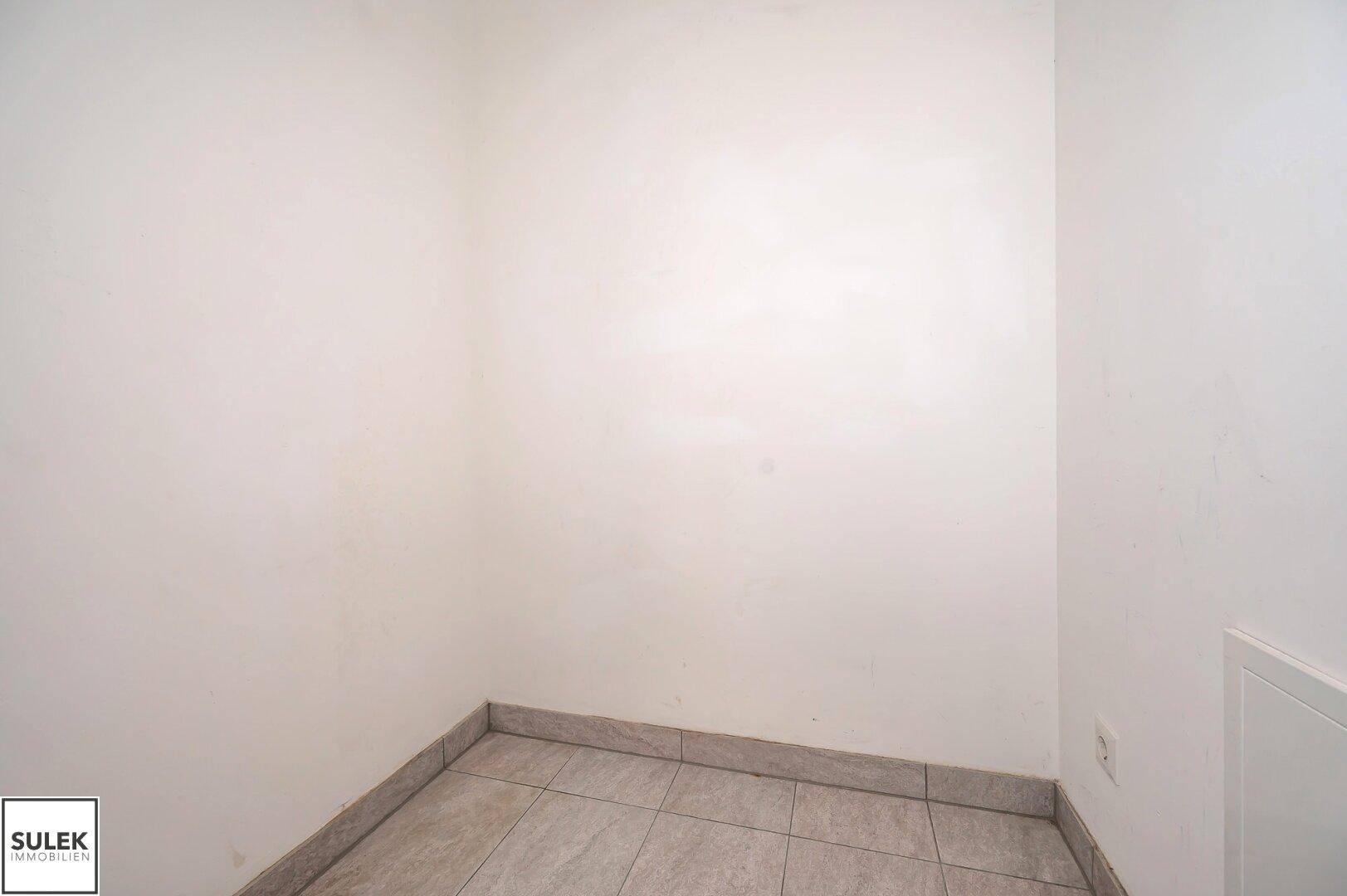 Kleiner, leerer Raum mit Fliesenboden, ideal als Abstellraum oder Speisekammer.