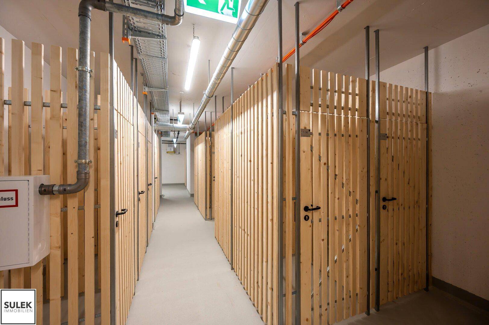 Praktischer Abstellraum im Keller mit individuellen Holzverschlägen und sichtbaren Installationen.