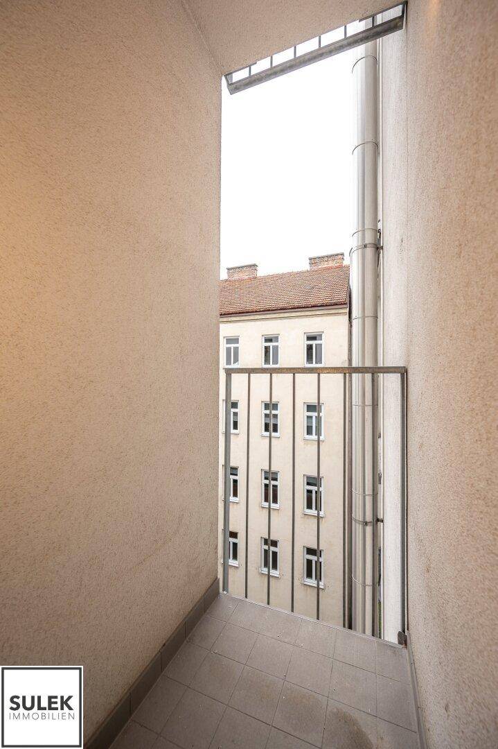 Schmaler Balkon mit Fliesenboden und Blick auf die gegenüberliegende Fassade.