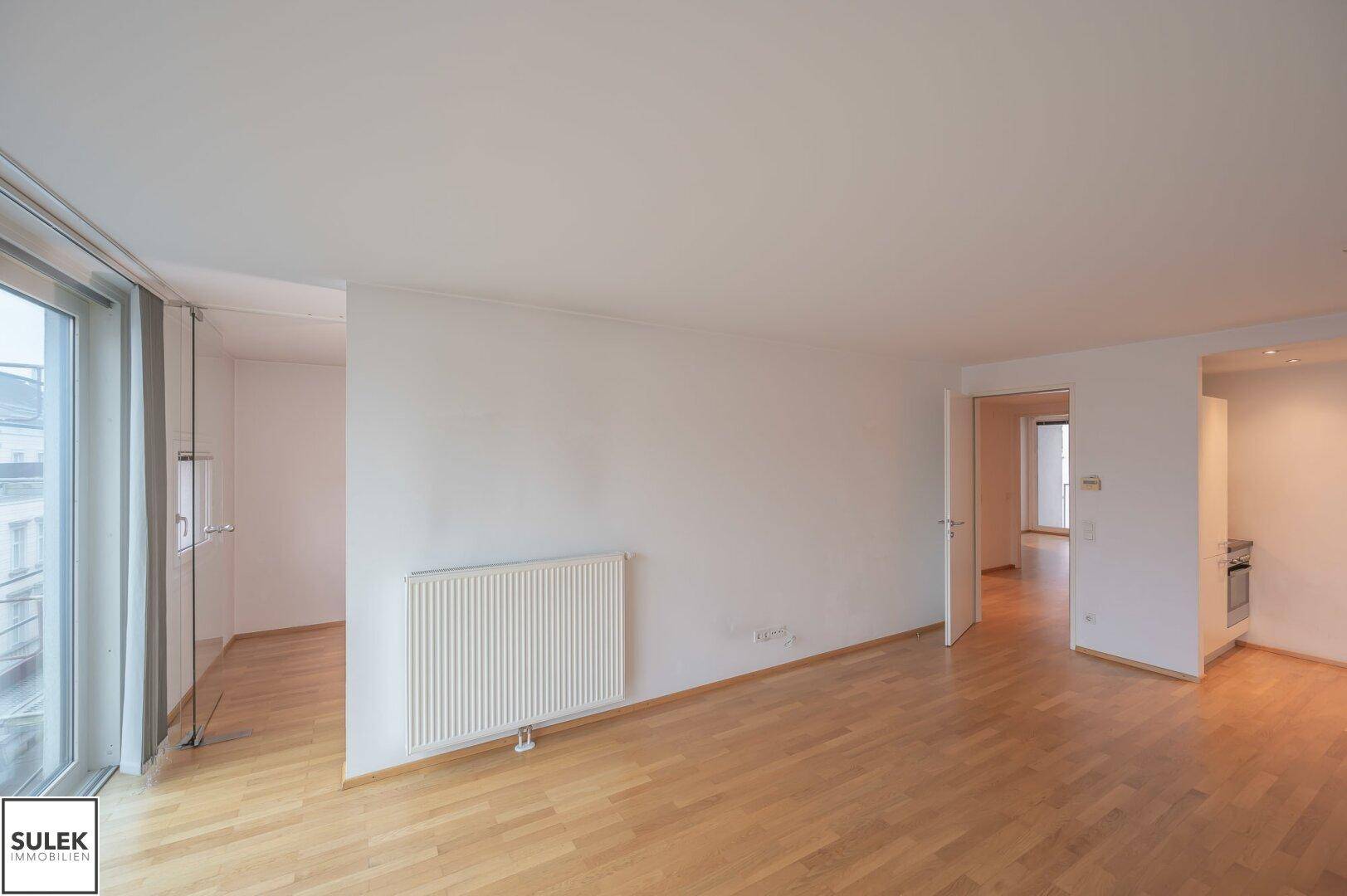 Großer, heller Wohn-Essbereich mit Holzfußboden und offener Verbindung zur Küchenzeile.