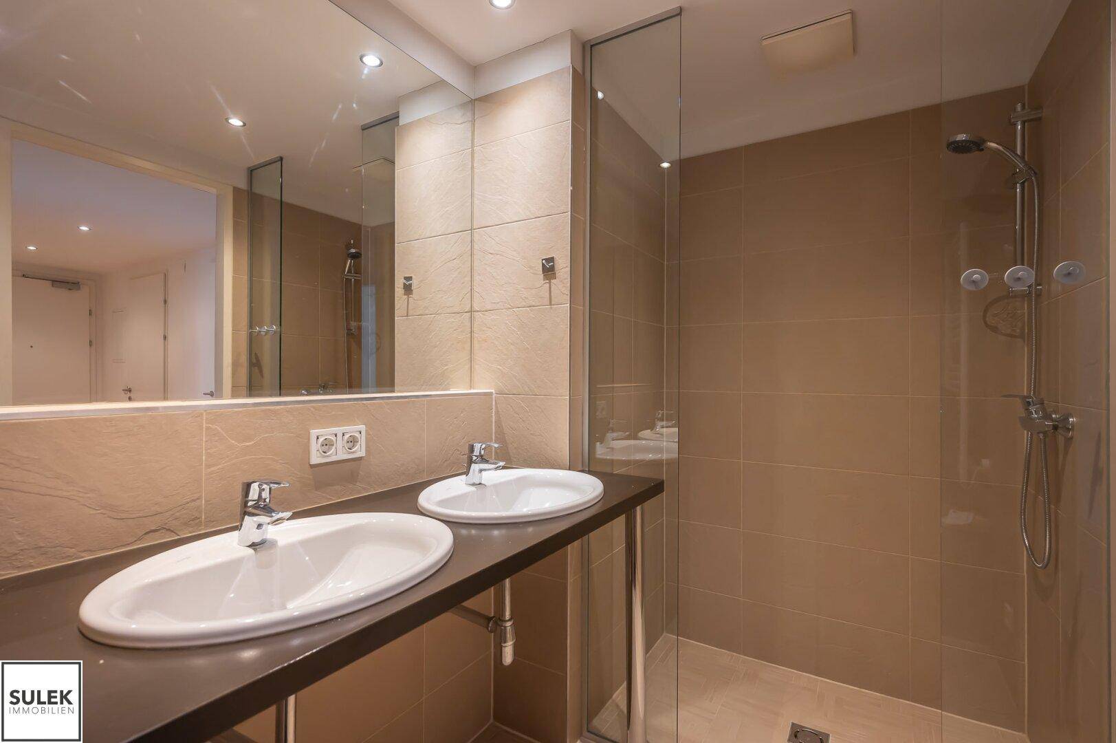 Modernes Badezimmer mit Doppelwaschbecken, großem Spiegel und begehbarer Dusche.
