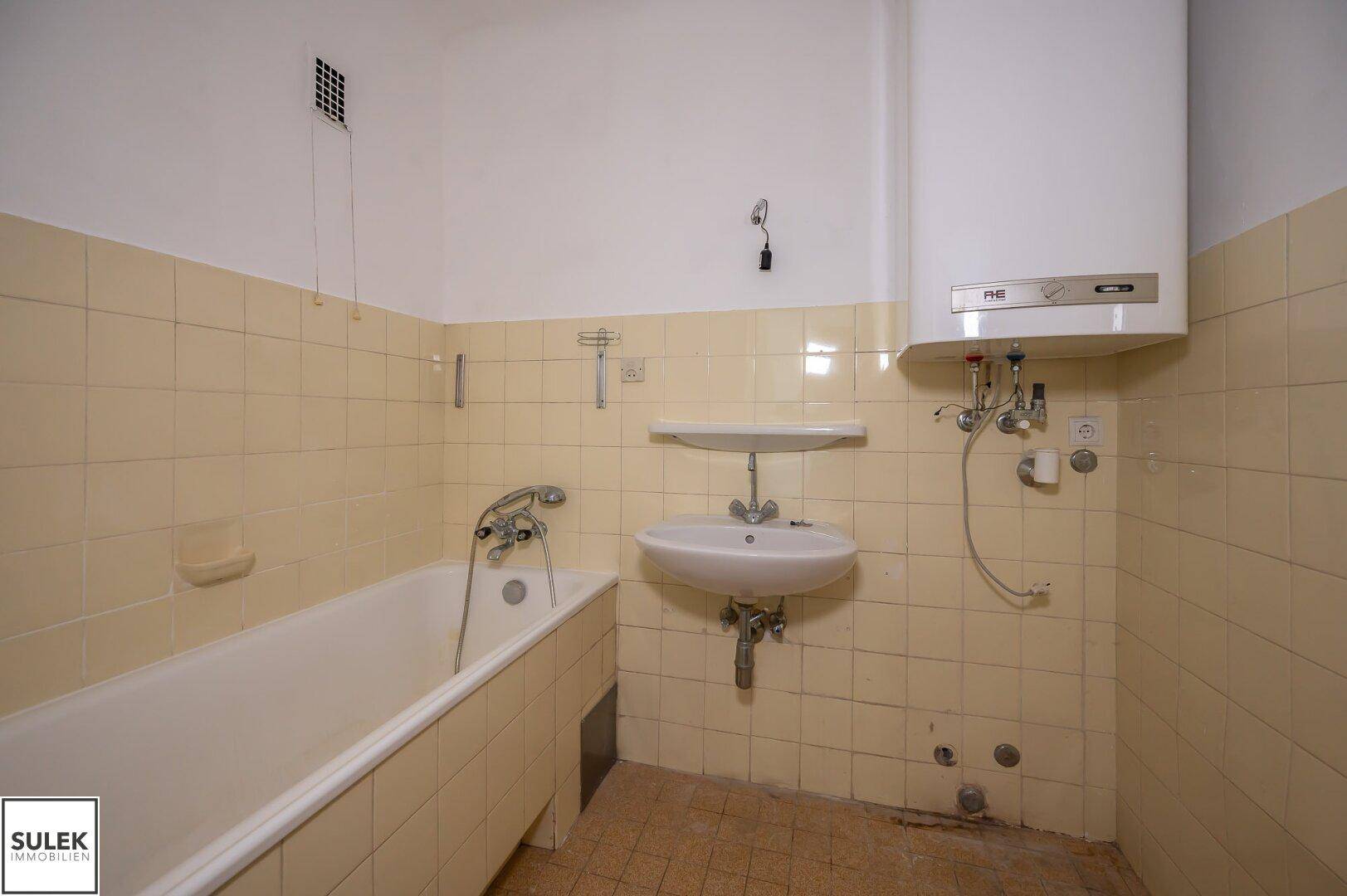 Badezimmer mit Badewanne, Waschbecken und gelben Fliesen, im Stil der 80er Jahre.
