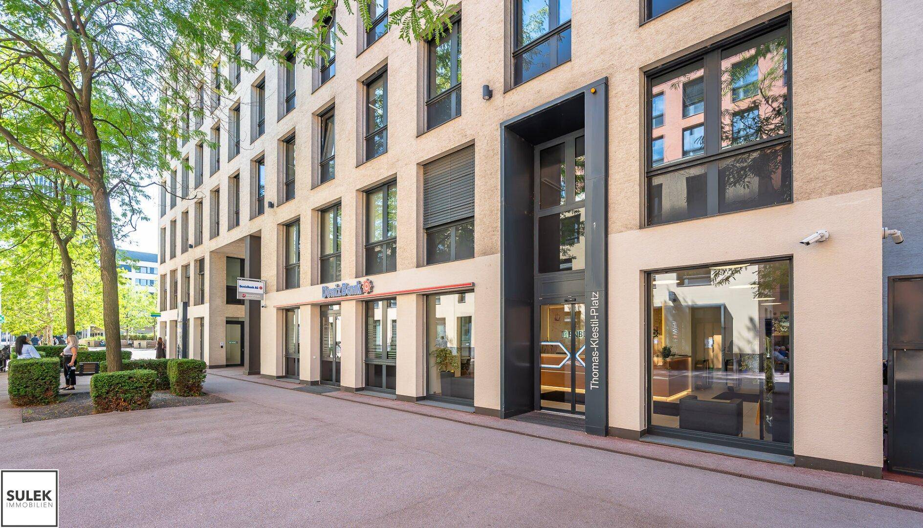 Moderne Gebäudefassade mit großen Fenstern und einem einladenden Eingangsbereich.
