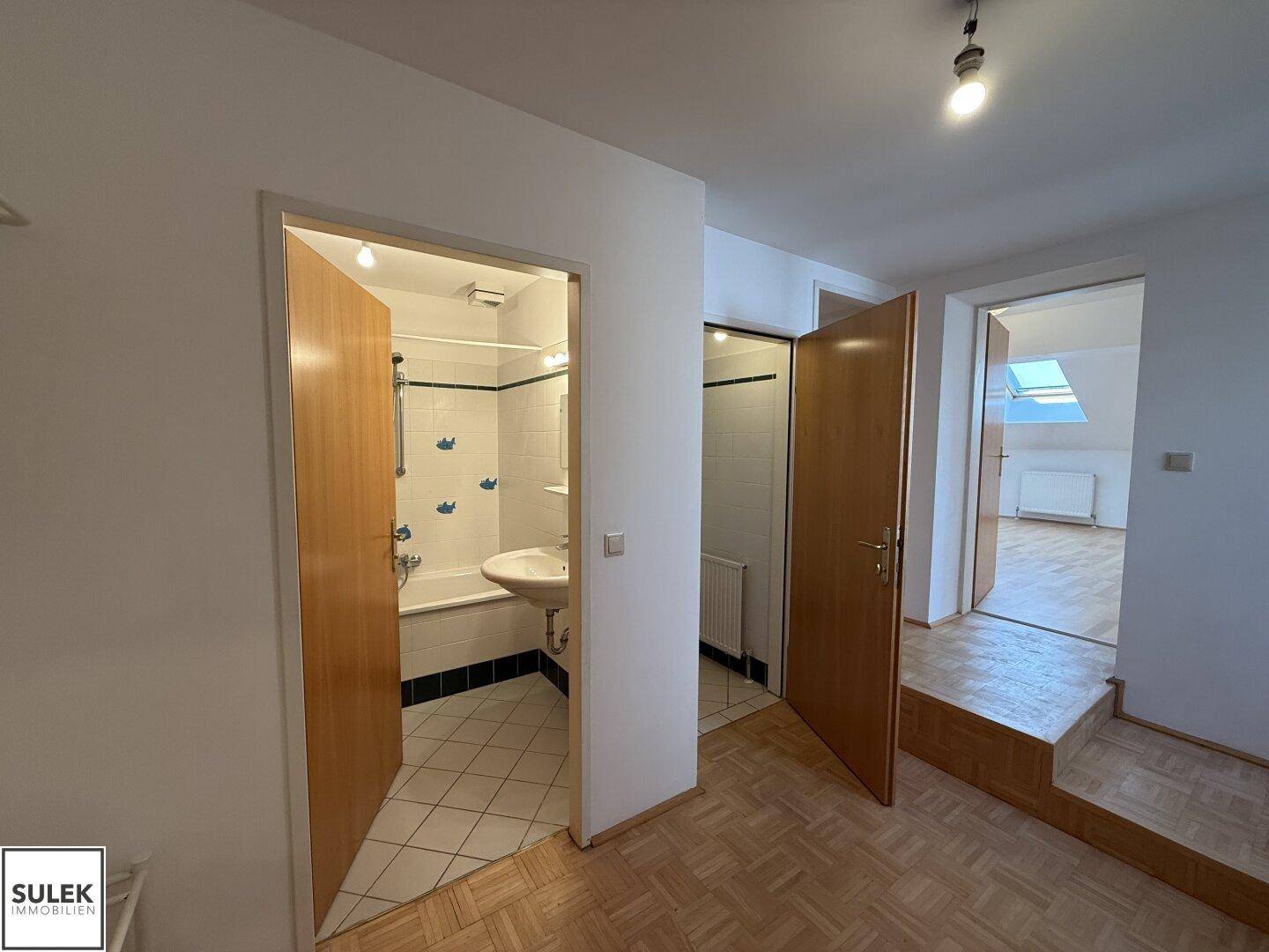Flur mit Zugang zum Badezimmer und einem hellen Dachzimmer.