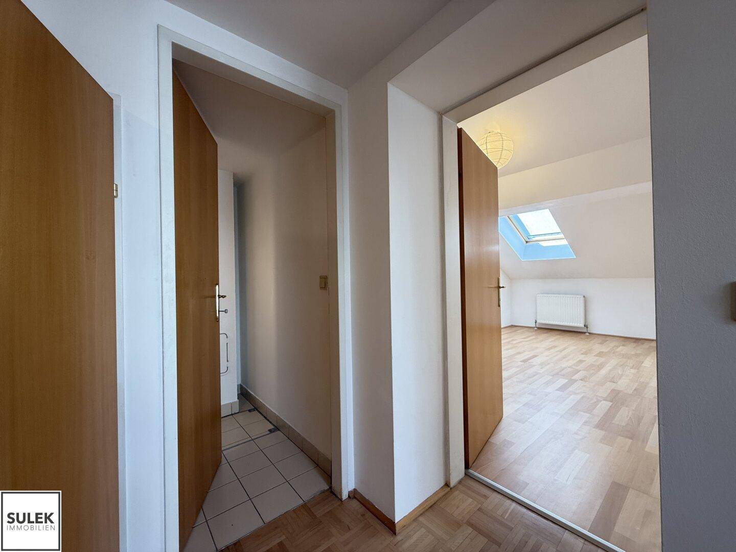 Flur mit Blick in ein helles Dachzimmer und Zugang zu weiteren Räumen.