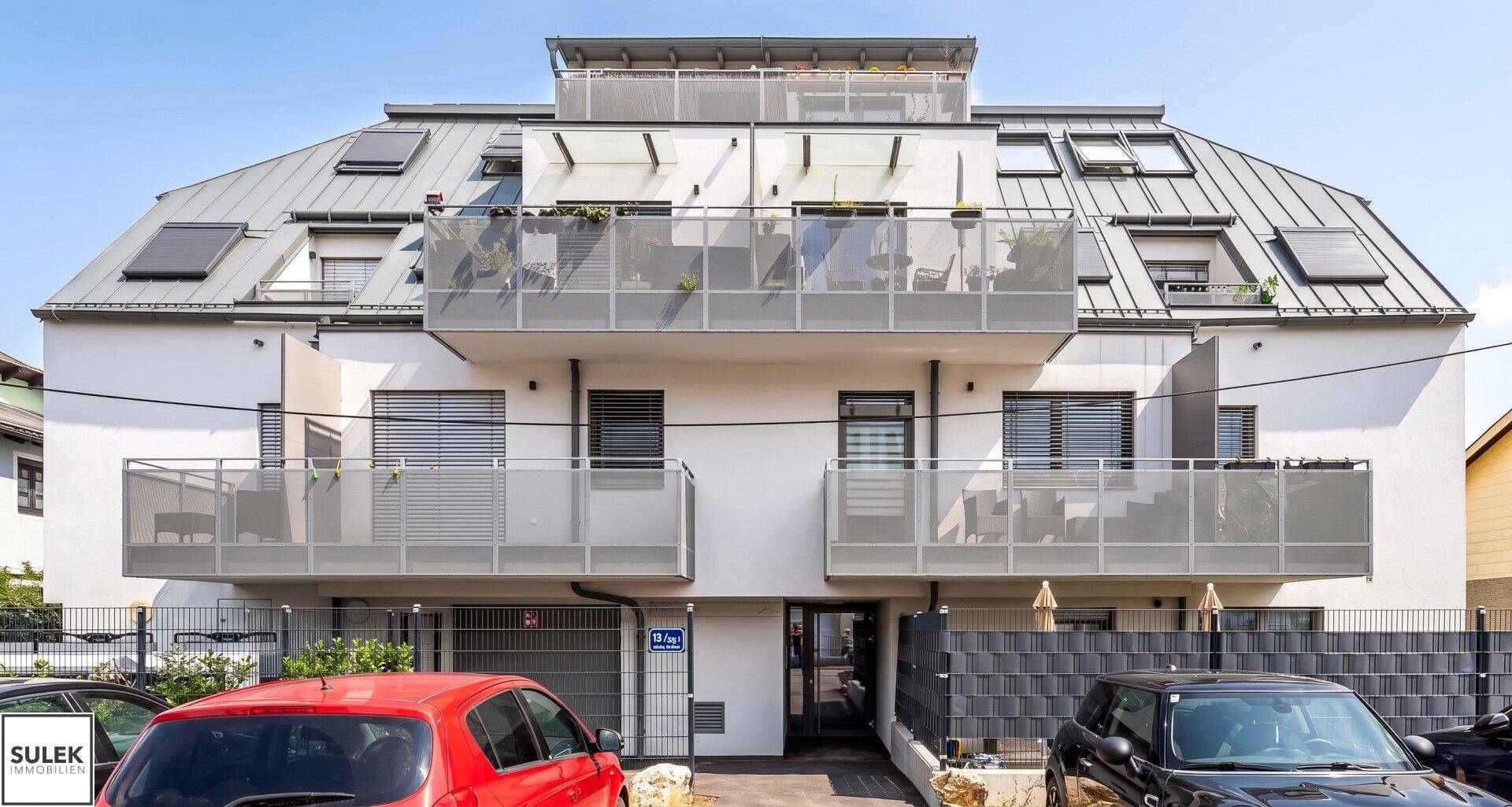Moderne Fassade des Mehrfamilienhauses mit mehreren Balkonen und großen Fenstern.
