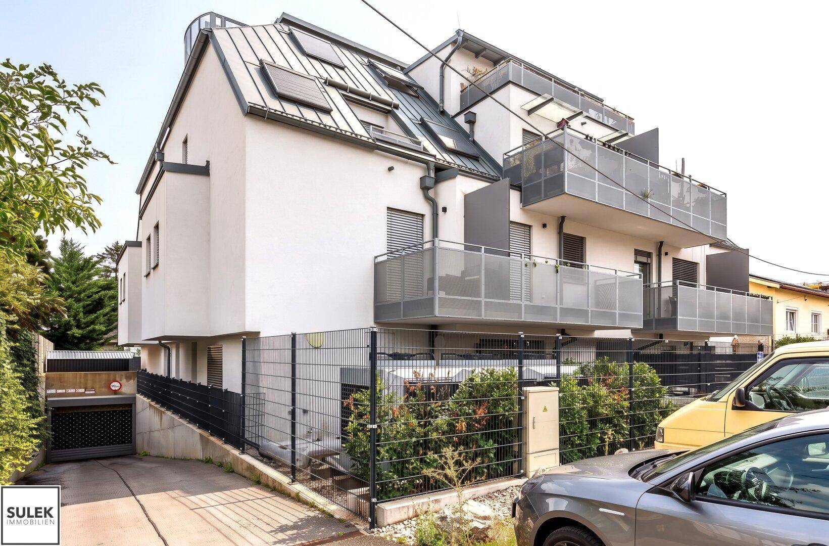 Seitenansicht des modernen Wohngebäudes mit Tiefgaragenzufahrt und Balkonen.