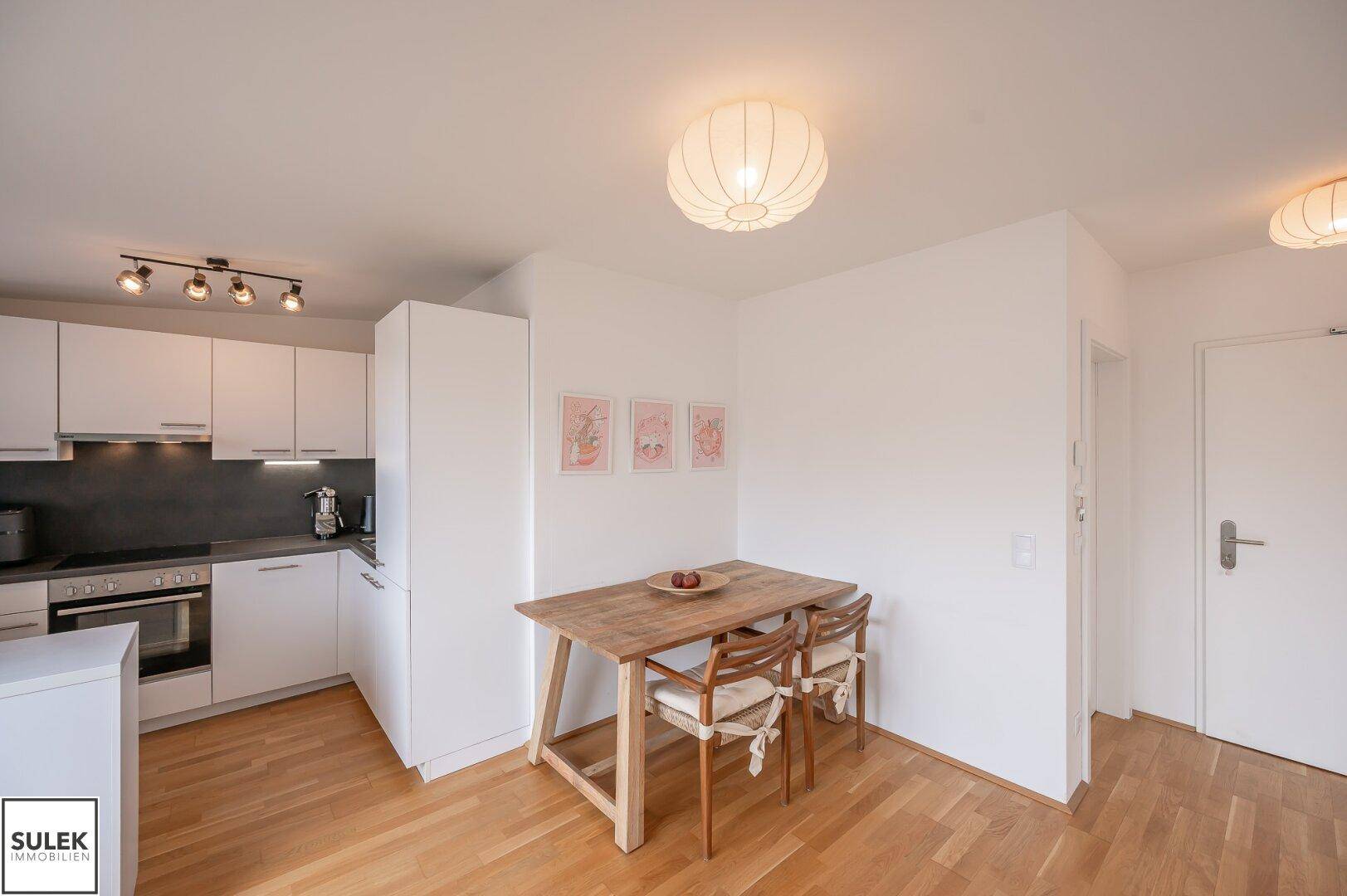 Gemütlicher Essbereich mit Holztisch und Stühlen, direkt neben der modernen Küche.