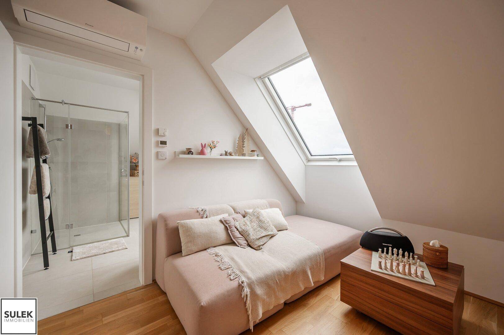 Gemütlicher Wohnbereich mit Sofa und Zugang zum modernen Badezimmer.