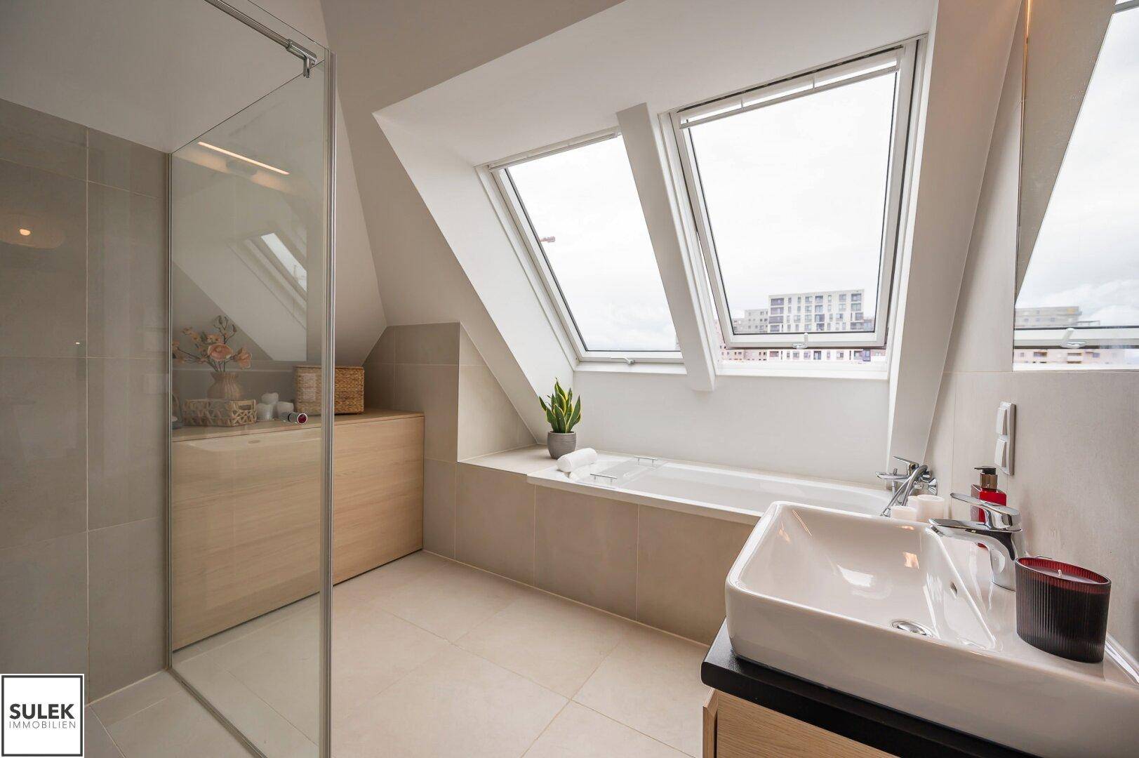 Helles Badezimmer mit Badewanne, Dusche und Dachfenstern für viel Tageslicht.