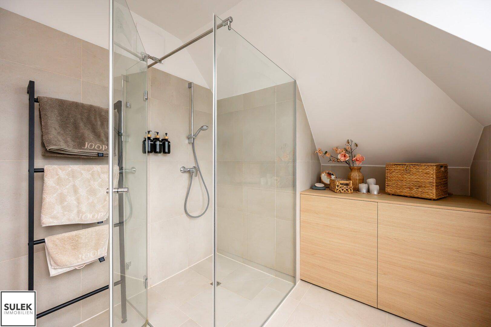 Geräumige begehbare Dusche mit Glasabtrennung und praktischem Handtuchhalter im modernen Bad.