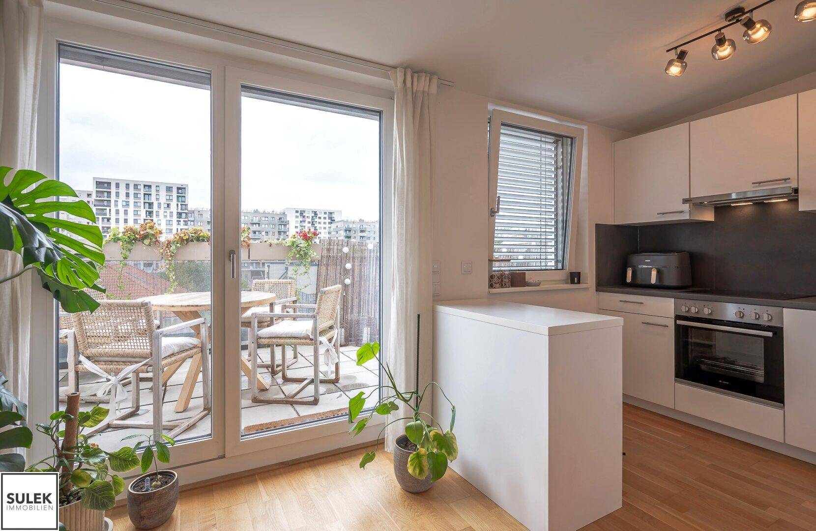 Offener Wohnbereich mit moderner Küche, Essbereich und direktem Zugang zur Terrasse.