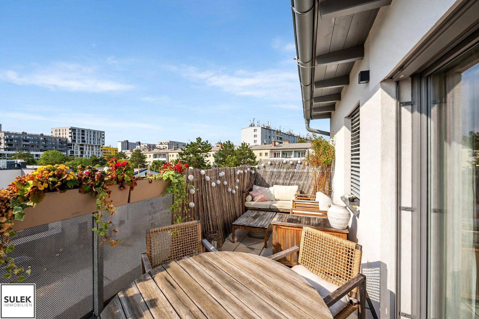 Geräumige Dachterrasse mit gemütlichen Holzmöbeln und Blick auf die umliegende Stadtlandschaft.
