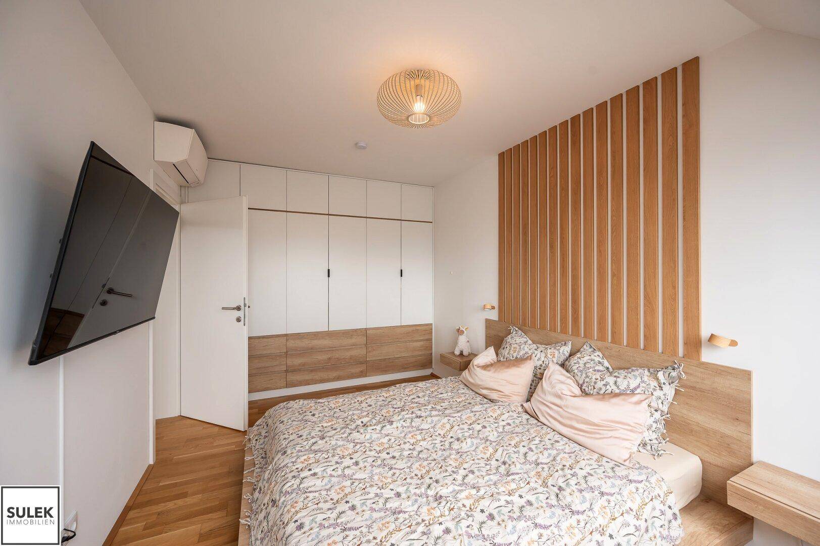 Modernes Schlafzimmer mit integrierten Kleiderschränken und stilvoller Holzwandverkleidung.
