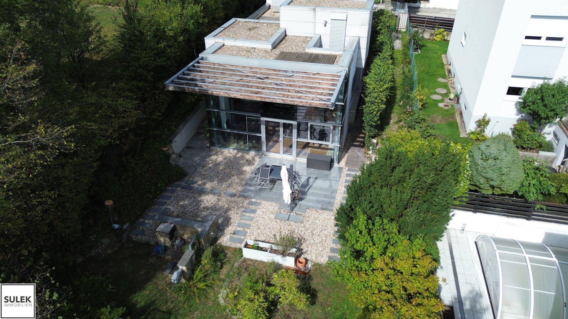 Luftaufnahme des modernen Hauses mit gepflegtem Garten und Außenbereich mit Sitzgelegenheiten, sehr einladend.