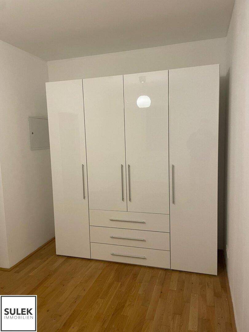 Geräumiges Schlafzimmer mit großem weißen Kleiderschrank und Holzboden.