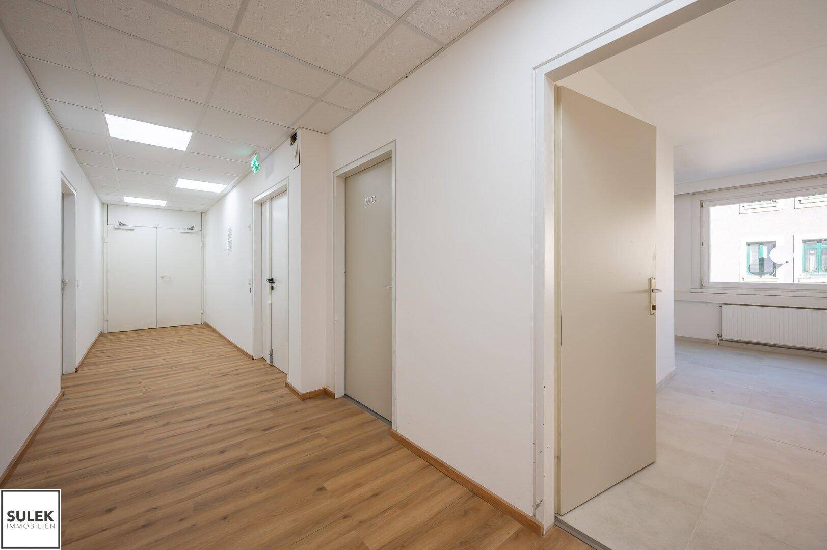 Langer, heller Flur mit Laminatboden und mehreren Türen zu den angrenzenden Räumen.