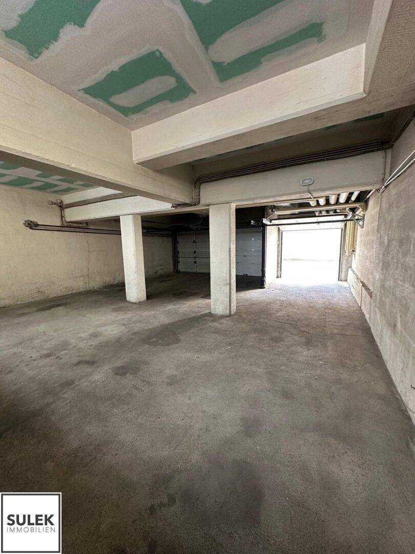 Geräumige Tiefgarage oder Lagerfläche mit Betonboden und tragenden Säulen.
