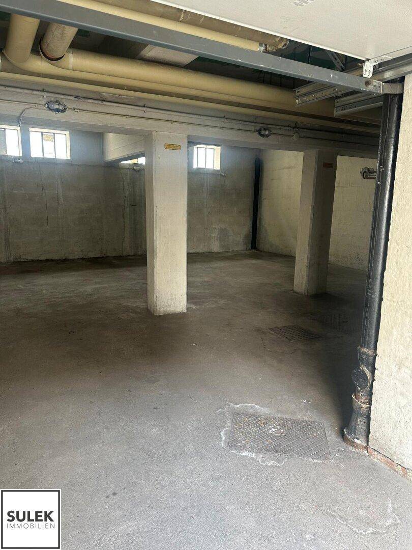 Großer Kellerraum mit Betonwänden, Säulen und kleinen Fenstern nahe der Decke.