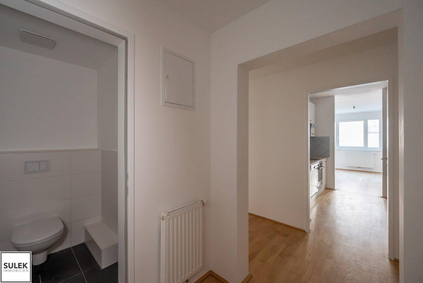 Flurbereich mit Zugang zu einer Gästetoilette und Blick in die angrenzende Küche.