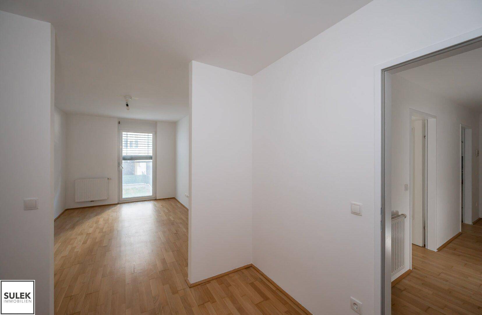 Heller, leerer Raum mit Parkettboden und Fenster mit Jalousien, ideal als Wohn- oder Schlafzimmer.