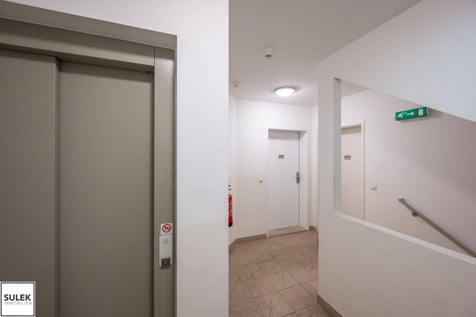 Gemeinschaftlicher Flurbereich mit Aufzug und Treppenhaus, in einem gepflegten Mehrfamilienhaus.