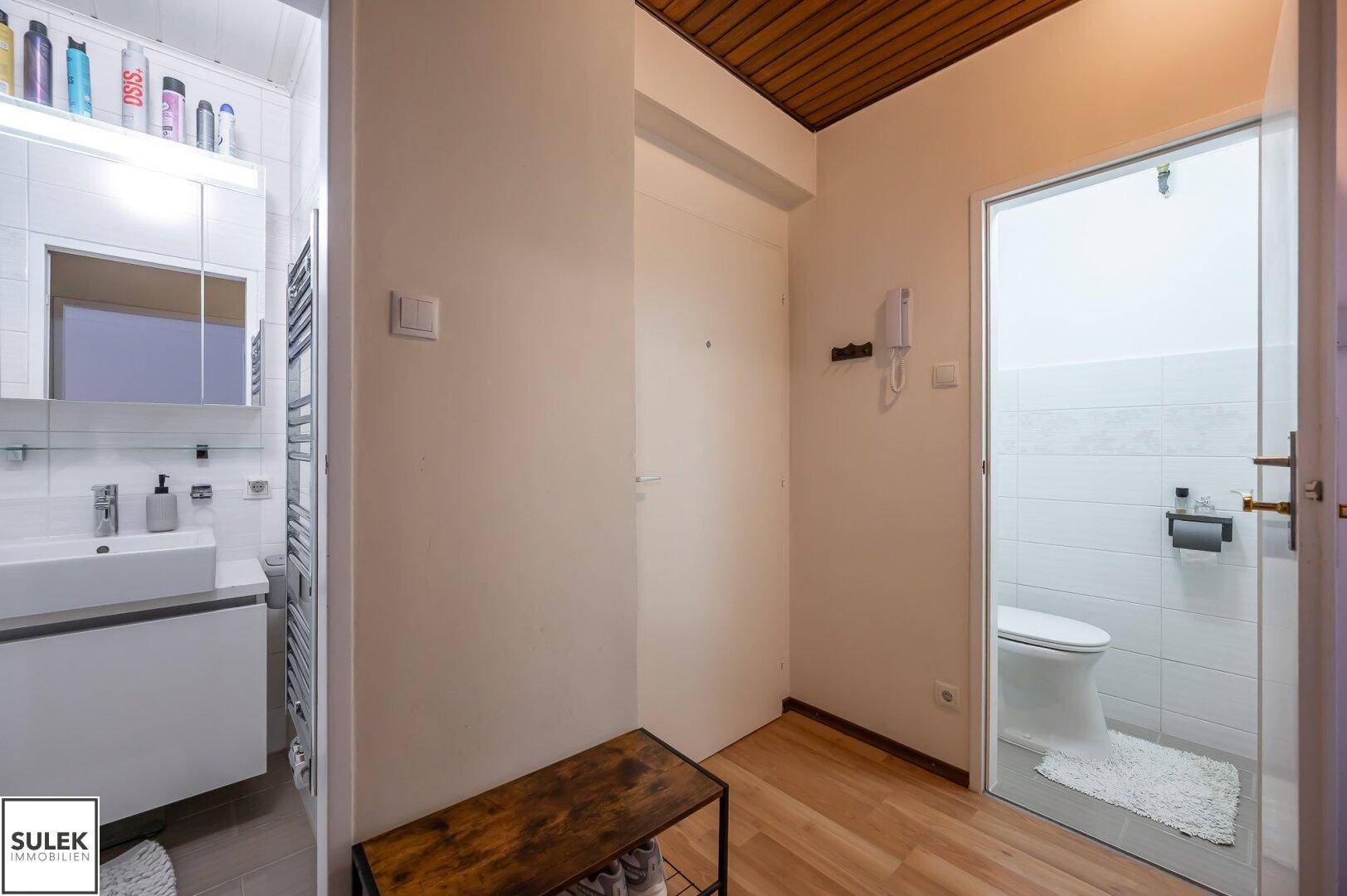 Flur mit Holzboden und Holzdecke, Zugang zu Badezimmer und separatem WC.