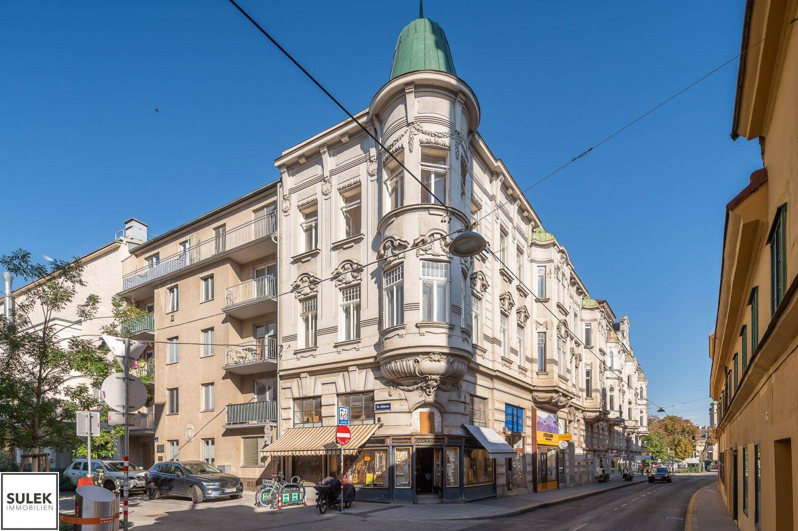 Historisches Eckgebäude mit reich verzierter Fassade und Geschäften im Erdgeschoss.