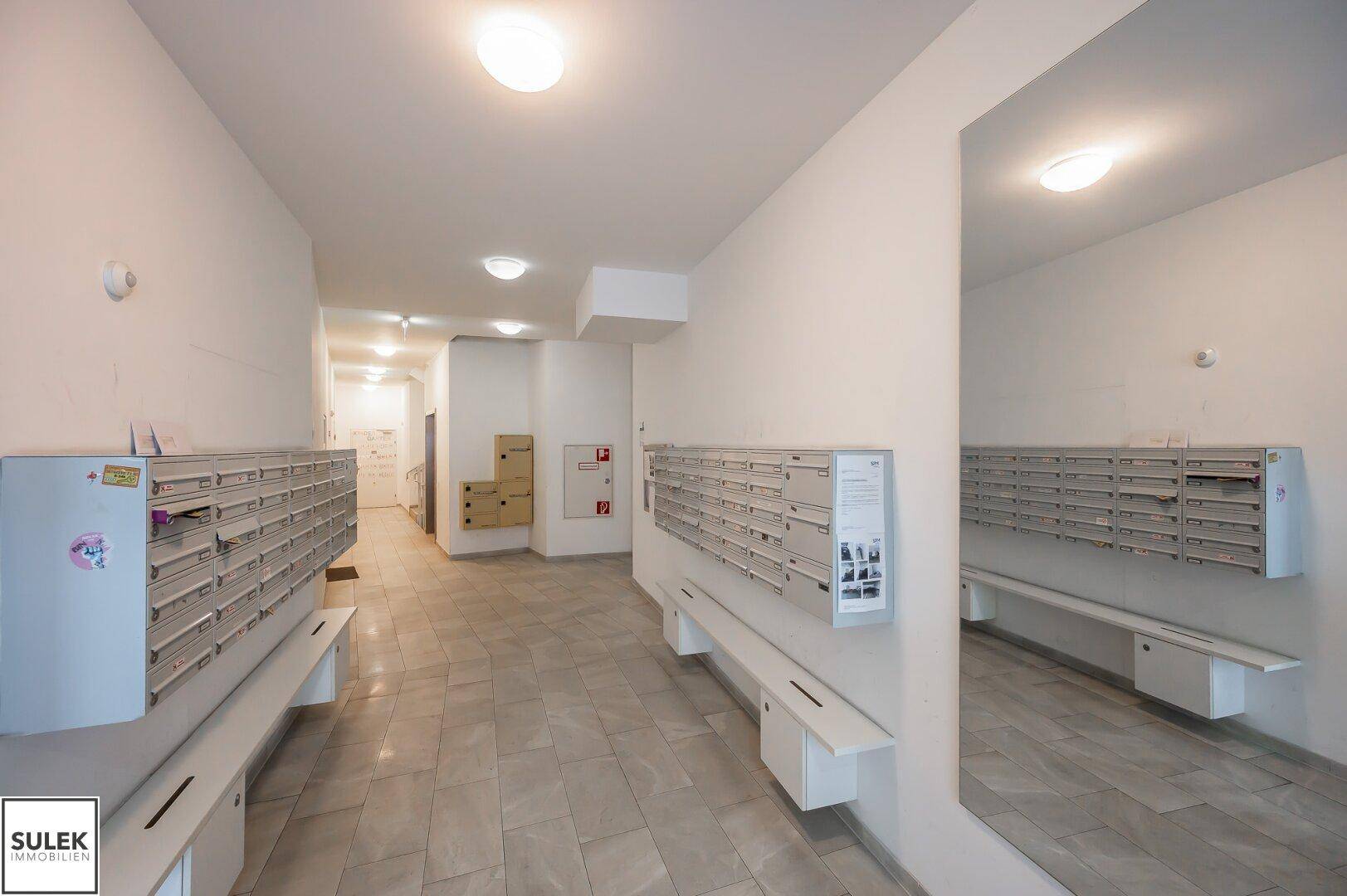 Geräumiger Eingangsbereich mit vielen Briefkästen und Sitzgelegenheiten.