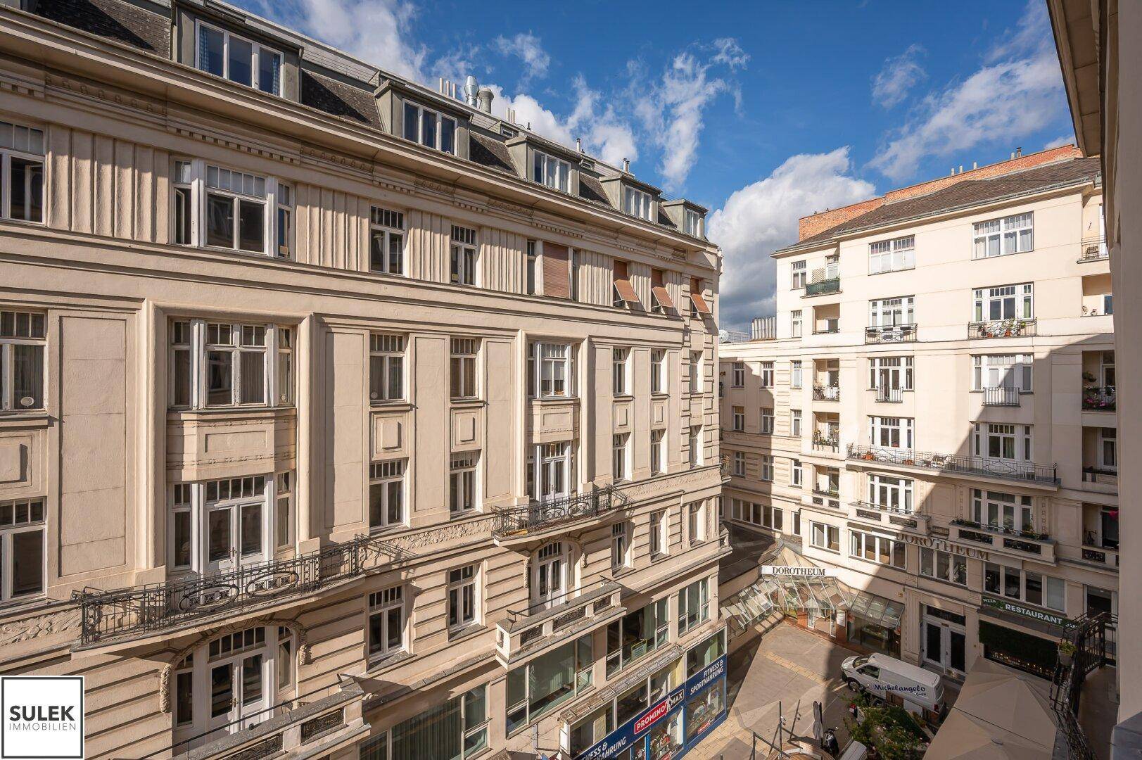 Historische Gebäude mit Balkonen und Geschäften im Erdgeschoss, unter einem bewölkten Himmel.