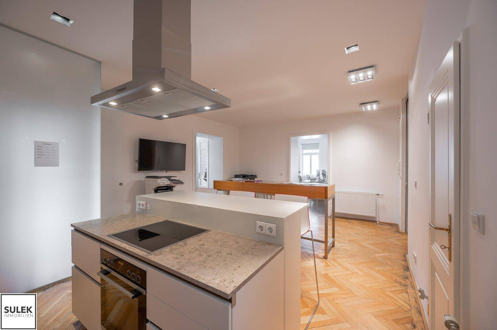 Moderne Küche mit Kochinsel, Induktionskochfeld, Dunstabzugshaube und integriertem Backofen.