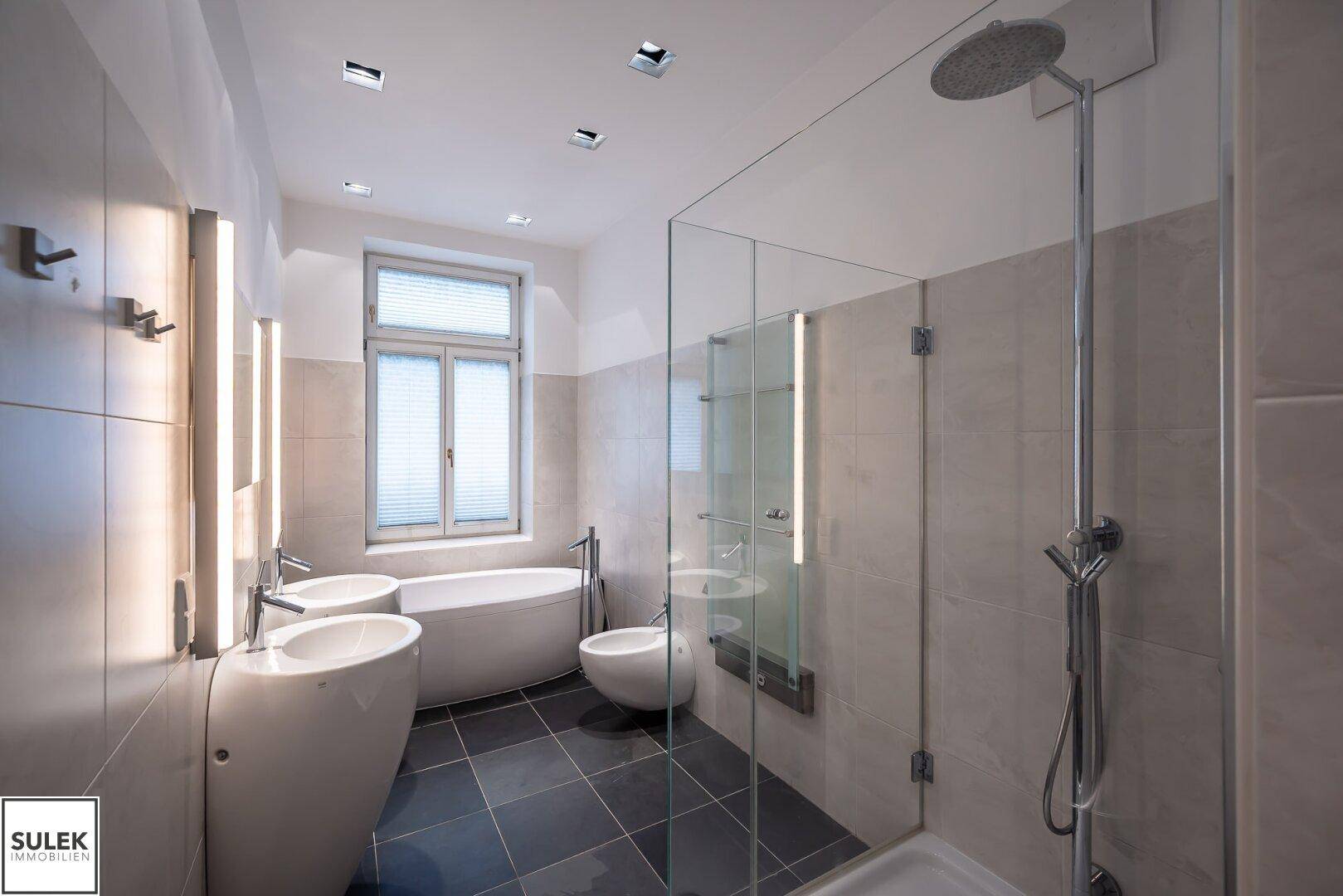 Modernes Badezimmer mit freistehender Badewanne, zwei Waschbecken und großer begehbarer Dusche.